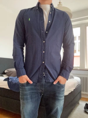 Mörkblå Ralph lauren skjorta - Snygg mörkblå Ralph lauren skjorta i bomull som sitter som en smäck.  Perfekt till jeans för en clean , enkel stil och även för lite finare tillfällen! As bra skick                                                     Kom pm för frågor!