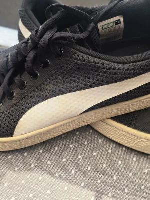 Svarta Puma sneakers med mesh - Snygga svarta sneakers från Puma med vit sula och klassisk vit logga på sidan. Ovandelen är i meshmaterial som ger bra ventilation och skön känsla. Lågt skaft och svarta skosnören för en clean look.
