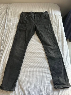 Mörkgrå slim fit jeans - Snygga mörkgrå slim fit jeans med klassisk femficksdesign och normal midja. Jeansen har raka ben och är tillverkade i ett mjukt denimtyg som ger en skön passform. Perfekta för dig som gillar en enkel och stilren look.
