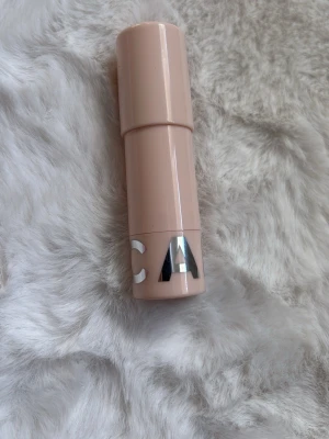 Nude läppbalsam i stift - Säljer ett stilrent läppbalsam i stift med nude-färgat hölje och silverdetaljer. Balsamet är vitt och har en klassisk rundad form som gör det enkelt att applicera. Perfekt att ha i väskan för återfuktade läppar hela dagen. Använd 1 gång.