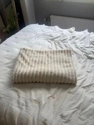 Vitt ribbat fleecefilt - Mysig vit fleecefilt med ribbad struktur. Perfekt att ha i soffan eller sängen för extra värme. Storleken är 100x150 cm och materialet är mjukt och fluffigt. Vet tyvärr inte vart den är köpt. Säljer även på vinted @caisaborelius