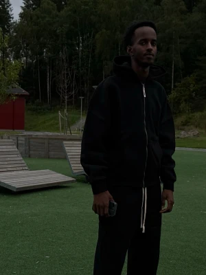 SOULMARK Tracksuit Svart  - SVART hoodie med dragkedja och huva. Hoodien har ribbade muddar, fickor på sidorna och en avslappnad passform. Tillverkad i mjukt material som ger en chill vibe och passar perfekt till streetwear-stilen. Hoodie och byxor ingår, oversized! S,M,L,XL finns. Kan fraktas i hela Sverige 