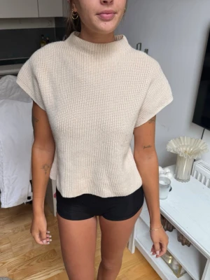 Beige ribbstickad topp  - Snygg beige ribbstickad topp med korta ärmar och hög hals