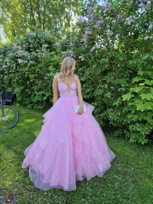 Rosa balklänning  - Drömmig balklänning i ljusrosa med volangkjol och spetsdetaljer upptill. Klänningen har snörning i ryggen och tunna band.man kan ha banden antingen på axlarna eller att dom hänger över armarna , jag är 161 cm jag hade klackar på mig och då var den bra i längden, jag har vanligtvis s/xs i kläder 