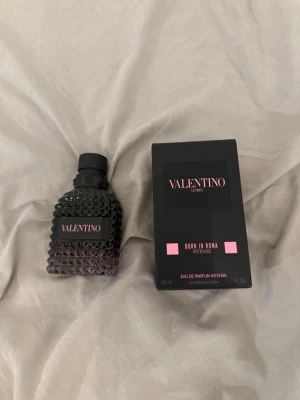 Valentino Born In Roma Intense 50ml - Valentino Born In Roma Intense är en parfym i en snygg svart flaska med nitar och rosa detaljer. Flaskan rymmer 50 ml och har en lyxig, modern design. Parfymen levereras med originalkartong i matchande svart och rosa färg.