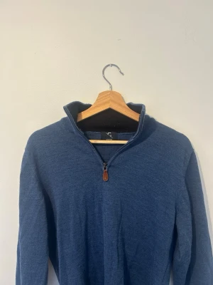 Blå halvzip tröja från Giovani - Snygg blå stickad tröja från Giovani med halvzip och hög krage. Tröjan har långa ärmar och är tillverkad i mjukt material som passar perfekt för kyligare dagar. Enkel men stilren design som funkar till det mesta.