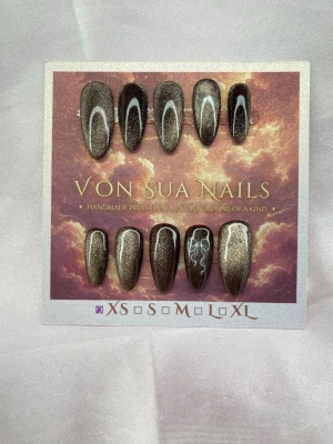 Praline(XS);Medium Almond - Snygga handgjorda press-on naglar i en skimrande cateye, brun nyans med vita rosetter. Naglarna har en elegant medium lång almondform och kommer i storlek XS: 14 mm, 11 mm, 11,5 mm, 10 mm, 8 mm. Perfekt för dig som vill ha unika och trendiga naglar utan salongsbesök.