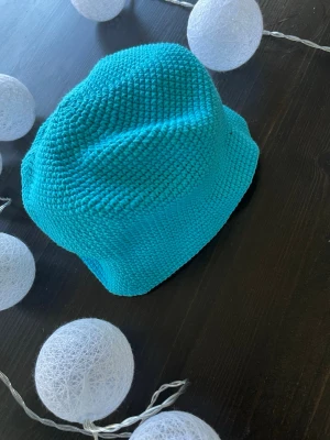 Turkos virkad bucket hat - Säljer en turkos bucket hat som är virkad i ett mjukt garn. Hatten har en klassisk form med nedvikt brätte och är perfekt för dig som vill sticka ut med färg. Passar till både streetwear och sommaroutfits. Mått på hatten storlek 62 barn 🌸