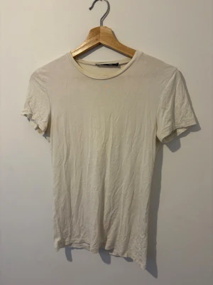 Klassisk vit t-shirt i bomull - En enkel och stilren vit t-shirt med rund hals och korta ärmar. Tillverkad i mjuk bomull och har en normal passform. Perfekt basplagg för alla tillfällen och lätt att matcha med andra plagg. (Inte tvättad på bilden!)