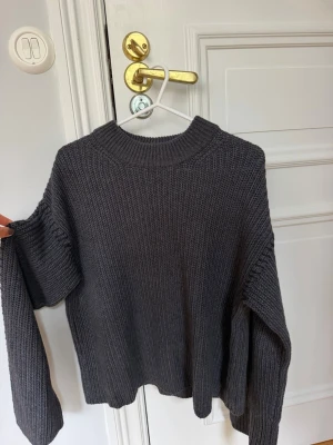 Grå stickad tröja - Grå stickad tröja med svarta detaljer längs ärmarna
