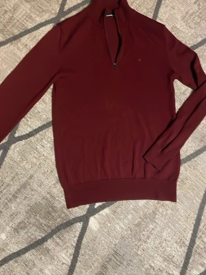 Vinröd halvzip från J.Lindeberg - Snygg vinröd långärmad tröja från J.Lindeberg med halv dragkedja och diskret logga på bröstet. Tröjan har ribbade muddar och är tillverkad i ett mjukt, tunt material som passar perfekt till lager-på-lager-stil. Slitage på slutet av mudden på ärmarna. Kontakta vid frågor🤩