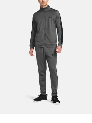 Grå träningsdress från Under Armour - Säljer en grå träningsdress från Under Armour med svarta detaljer på ärmar och ben. Setet består av en zip-jacka och matchande byxor, båda med logga på bröst och lår. Perfekt för gymmet eller sportaktiviteter.