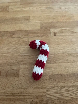 Virkad polkagris - Handgjord virkad polkagris i rött och vitt, tillverkad av mjukt garn. Perfekt som dekoration till jul eller som en söt detalj i hemmet. Formen är klassisk böjd polkagris och materialet är fluffigt garn.