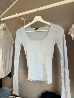 Ljusblå långärmad topp 🩵 - Snygg ljusblå långärmad topp med rundad urringning och slits i ärmen. 🪩 Toppens enkla design gör den lätt att matcha och den har en slim passform som sitter snyggt på kroppen. Perfekt för dig som gillar stilrena basplagg. 🤩😍