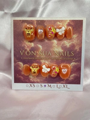 JollyPomPom (M);ExtraShortOval  - Handgjorda press-on naglar i glittrig orange med 3D-dekorationer som Pompompurin, vita rosetter, hjärtan och små gula detaljer. Naglarna har en extra kort, rundad form och är perfekta för dig som vill ha något gulligt och unikt på händerna.M: 16 mm, 12 mm, 12,5 mm, 11,5 mm, 10 mm