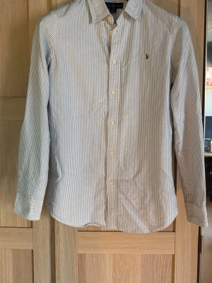 Ralph Lauren skjorta - blå/vit randig  - Slim passform. Har en liten fläck (se bild 4), annars bra skick. Vid frågor eller funderingar är det bara att skicka ett meddelande!