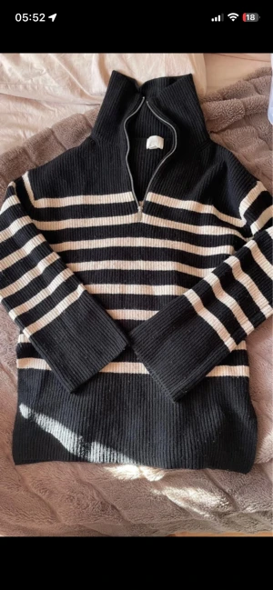 Svartvit stickad tröja från H&M - Säljer en svart stickad tröja från H&M med vita horisontella ränder. Tröjan har dragkedja vid halsen och ribbstickade muddar vid ärmslut och nederkant. Perfekt för dig som gillar en enkel men snygg stil. Är en aning nopprig 