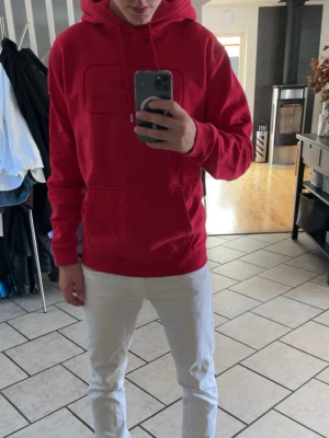 Röd hoodie från Sergio Tacchini - Snygg röd hoodie från Sergio Tacchini med broderad logga på bröstet. Klassisk känguruficka framtill, ribbade muddar och justerbar huva med dragsko. Perfekt för en avslappnad och sportig stil. Mjuk bomullskänsla.