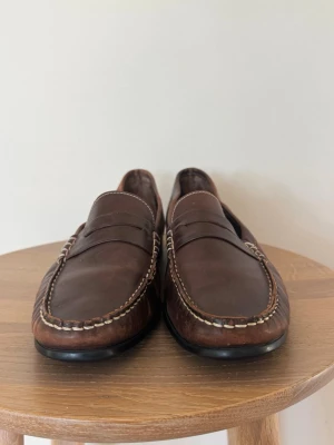 Paraboot Penny Loafers – Brunt läder – UK 7 / EU 41 - Paraboot penny loafers i brunt läder, herrmodell i UK 7 / ca EU 41. Klassisk fransk loafer med handsydd moccasin-konstruktion, penny strap och fin naturlig patina.  Bra begagnat vintage-skick med färgskiftningar och mindre märken i lädret. Sulorna har gott om liv kvar.  Made in France.