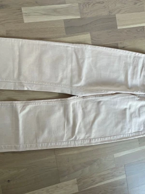 Beige raka jeans - Säljer ett par ljusbeige/ aprikos jeans med rak passform och klassiska bakfickor. Jeansen har en enkel och stilren look, perfekta att matcha med olika outfits. 