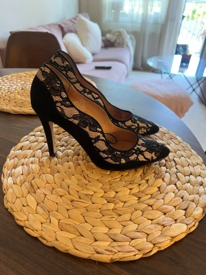 Spets pumps med hög klack - Säljer ett par eleganta pumps med spetsdetaljer i svart och nude. Skorna har spetsig tå, hög klack och vågig kant längs öppningen. Otroligt snygga men säljer då jag tyvärr ej kan gå i höga klackar 🫠💞Inga yttre skavanker som syns, men har lite fläckar på sulan. Storlek 40 och passar mig med ganska breda fötter 
