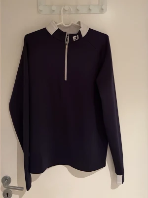 Footjoy Quarter-zip blå - Marinblå quarter-zip ifrån FootJoy. Lite sliten vid muddarna, annars gott skick. 