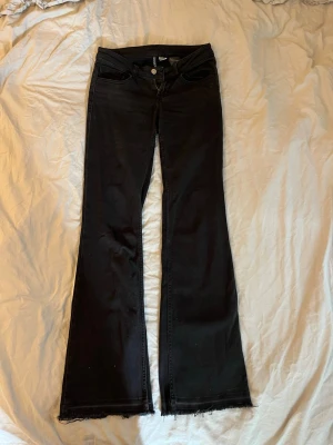 Svarta lågmidjade bootcut jeans - Snygga svarta lågmidjade bootcut jeans från H&M i storlek 36, lite stretchiga i materialet, sömnen längst med är neddragen. 