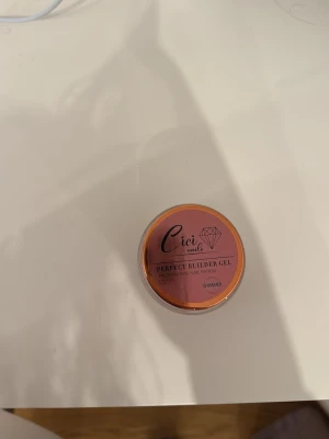 Cici Nails Perfect Builder Gel Shimmer - Byggel från Cici Nails i en snygg rosa-brun nyans med shimmer. Perfekt för att bygga och forma naglar med professionellt resultat. Kommer i en rund burk med skruvlock. Gelen har en glansig finish och passar till kreativa nageldesigner. 15g