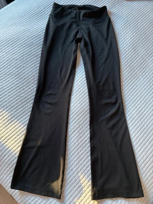 Svarta bootcut träningsbyxor SOC storlek 164 - Säljer ett par svarta träningsbyxor från SOC i storlek 164. Byxorna har bootcut-modell med hög midja och är tillverkade i ett stretchigt funktionsmaterial som håller dig torr och bekväm. Perfekta för träning!