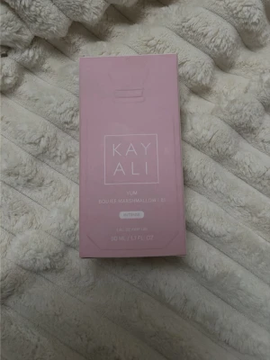 Kayali Yum Boujee Marshmallow parfym - Kayali Yum Boujee Marshmallow B1 Intense är en parfym i en matt, ljusrosa flaska med vit, multifacetterad kork. Flaskan rymmer 50 ml och har en modern, stilren design. Doften är söt och gourmand, perfekt för dig som gillar unika och trendiga parfymer.