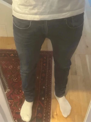 Mörkblå anbass - Snygga mörkblå slim fit jeans med klassisk femficksdesign och smal passform. Jeansen har diskreta sömmar och sitter tight över benen för en modern look. Perfekta för dig som gillar stilrena och enkla jeans till vardags.