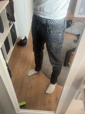 Replay ambas - Säljer ett par svarta slim fit jeans med tydliga vita kontrastsömmar och klassiska fem fickor. Jeansen har en modern passform och är tillverkade i denim. Perfekta för dig som gillar en stilren men ändå edgy look.