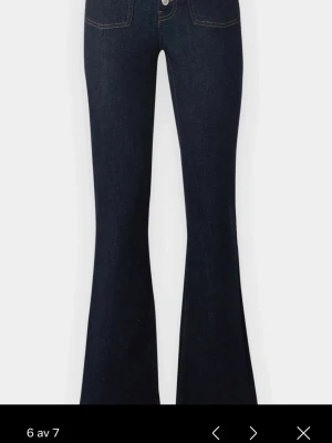 Mörkblå bootcut jeans med hög midja - Säljer ett par mörkblå bootcut jeans med hög midja och utsvängda ben. Jeansen har dubbla knappar framtill och dekorativa sömmar vid fickorna. Använda en gång!! Perfekta till hösten!!!