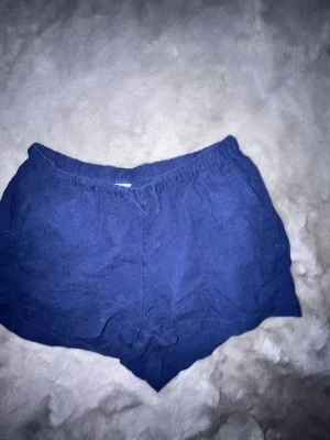 Mörkblå shorts från Lindex - Snygga mörkblå shorts från Lindex med elastisk midja och avslappnad passform. Tillverkade i ett mjukt material som känns skönt mot huden. Perfekta för varma dagar och enkla att matcha med olika toppar.