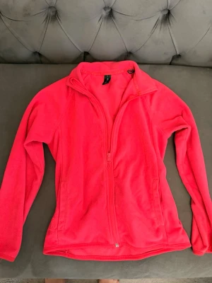 Rosa fleecejacka från 157 Funk - Säljer en mjuk och skön rosa fleecejacka från 157 Funk. Jackan har hel dragkedja framtill, hög krage och långa ärmar. Perfekt för kyliga dagar och enkel att slänga på sig över en hoodie eller t-shirt.