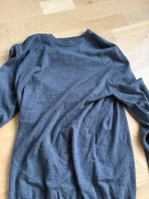 Blå merinoulltröja Dressmann - Blå stickad tröja från Dressmann i mjuk merinoull. Klassisk rund halsringning och lång ärm, perfekt för lager på lager. Enkel och stilren design som passar till det mesta.