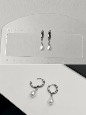 Silvriga hoops med vita pärlor - Snygga örhängen i form av silver färgade hoops med hängande vita pärlor. Enkla men ändå eleganta, perfekta för att lyfta vilken outfit som helst. Pärlorna ger en klassisk touch medan den blanka metallen känns modern.
