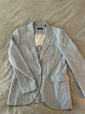 Randig kavaj från Matinique - Riktigt fet blazer från Martinique. Med den blå vita fräscha färgen så är det ett plagg som funkar både casual med en t shirt under eller likaså med skjorta vid finare tillställningar. Nypris på cirka 3000kr, jag säljer för endast 950kr!!
