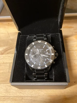 Svart kronografklocka i svart keramik - Stilren svart kronografklocka av keramik och markerad vridring. Klockan har flera urtavlor och tydliga indexmarkeringar. Perfekt accessoar för dig som gillar en sportig men ändå elegant look. Refnr: AR70010 ”World Explorer” svart keramik
