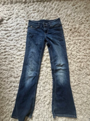 Mörkblå bootcut jeans - Säljer ett par mörkblå bootcut jeans med klassisk femficksmodell och lätt slitningar framtill. Jeansen har normal midja och är tillverkade i denim med snygg tvätt. Perfekta för dig som gillar en avslappnad men ändå trendig look.