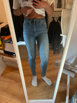 Nakd Blå high waist skinny jeans - Säljer ett par ljusblå high waist skinny jeans med klassisk femficksdesign. Materialet är stretchigt denim som sitter tajt och bekvämt.