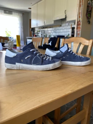 Philippe Model skor - Säljer ett par mörk blå Philippe Model skor i mocka med vita detaljer. Är använda men fortfarande i väldigt bra skick som man ser på sulan med i princip ingen heel drag. Hör av dig vid frågor eller om du vill ha extra bilder. Priset är inte hugget i sten. 