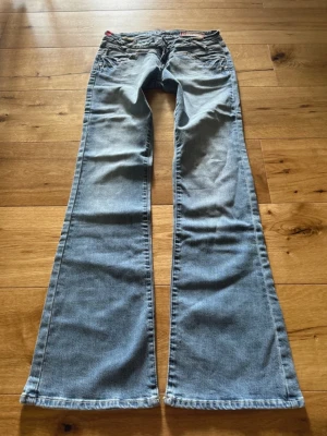 Lågmidjade utsvängda jeans från O’lala - Lågmidjade utsvängda jeans från O’lala. 🩷 Det står storlek 38 men tycker de passar mer 34. Jeansen är mer blå i verkligheten. Det är ljuset som gjorde att dem ser mer grå ut. Älskar dessa men tyvärr för stora för mig😓  Midjemått tvärsöver: 35 cm. Innerbenslängd: 80 cm.
