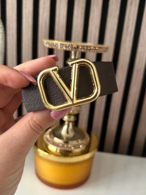 Brunt  bälte med gulddetalj -  Bältet är gjort i skinn och har en stilren design som passar till många olika outfits. Perfekt accessoar för att lyfta din look.