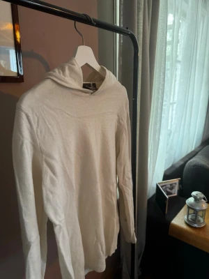 Vit hoodie från Oscar Jacobson XS - Säljer en stilren vit hoodie från Oscar Jacobson i storlek XS. Cashmere vilket ger en mjuk, tunn stickad känsla. Hoodien har långa ärmar och en klassisk huva. Perfekt för dig som gillar minimalistisk och clean stil.