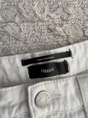 Vita shorts från Filippa K - Snygga vita shorts från Filippa K med rå kant nertill och två bakfickor. Klassisk femficksmodell med bälteshällor och knapp med logga. Perfekta för varma dagar och har en enkel, stilren look.