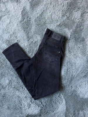 Replay jeans  - Snygga svarta Replay Anbass jeans med smal passform och stretchigt material. Klassisk femficksmodell med silverfärgade nitar och knapp. Passar perfekt till en avslappnad eller trendig look.
