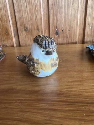 Keramisk fågel prydnadsfigur - Unik handgjord fågel i keramik med bruna, beige och vita nyanser. Fågeln har detaljerad fjäderstruktur och rund form, perfekt som dekoration i hemmet eller som present till någon som gillar konst och inredning.