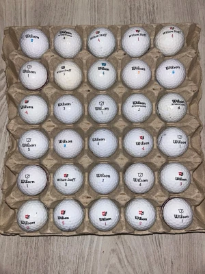30 Wilson golfbollar  - Säljer ett set med 30 stycken vita golfbollar från Wilson, flera med olika nummer och logotyper. Bollarna är runda och har klassisk dimple-yta. Perfekt för dig som vill fylla på golfbagen inför säsongen. Alla är tvättade och spelas med som nya.