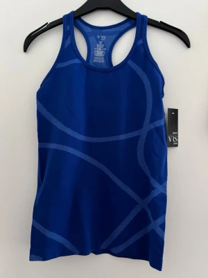 Blått sportlinne från VRS - Snyggt blått sportlinne från VRS med racerback och ljusare blå grafiskt mönster. Tillverkat i ett stretchigt och snabbtorkande material som passar perfekt till träning och gym. Linnet har en kroppsnära passform och breda axelband.
